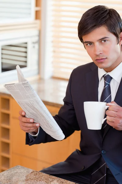 Portrait of a businessman drinking tea while reading a newspaper — Stock Photo, Image