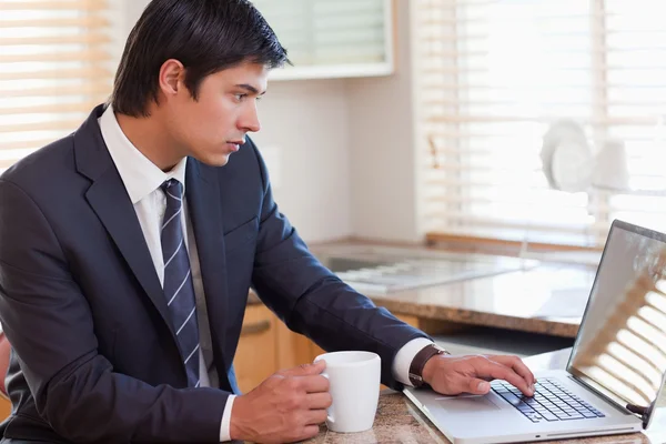 Homem trabalhando com um laptop enquanto bebe café — Fotografia de Stock