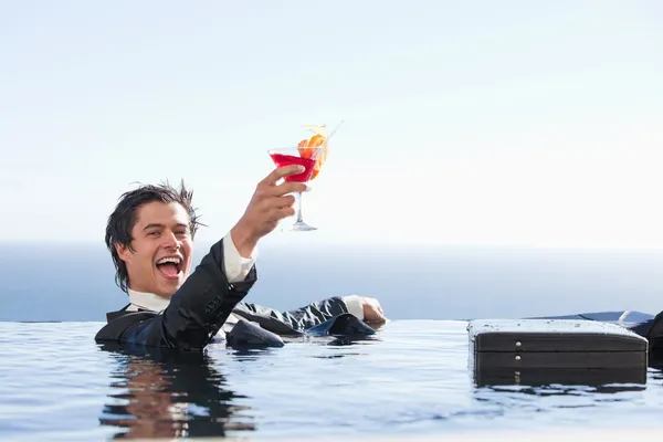 Восхитительный бизнесмен отдыхает в бассейне с коктаем — стоковое фото