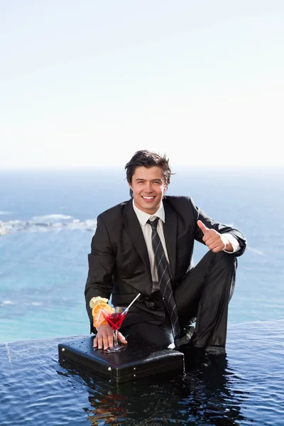Portrait of a businessman posing with a cocktail on a briefcase — Stock Photo, Image