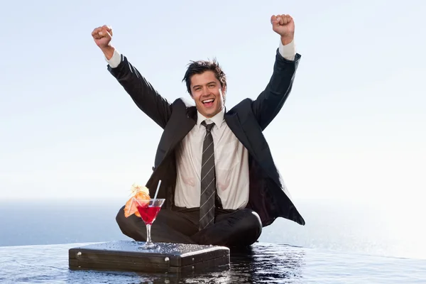 Businessman relaxing with a cocktail and his fists up — Stock Photo, Image
