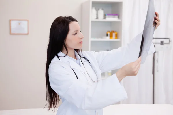 Junger Arzt schaut sich eine Reihe von Röntgenaufnahmen an — Stockfoto