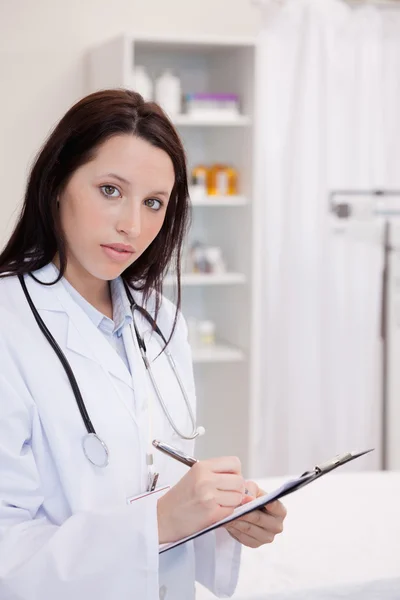 Female doctor writing on her notepad — Stock Photo, Image
