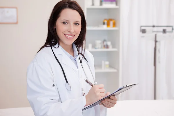 Sorridente medico femminile prendere appunti — Foto Stock