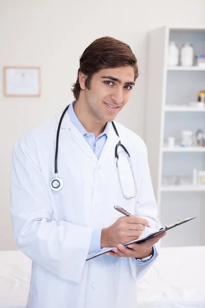 Smiling male doctor taking notes — Stock Photo, Image