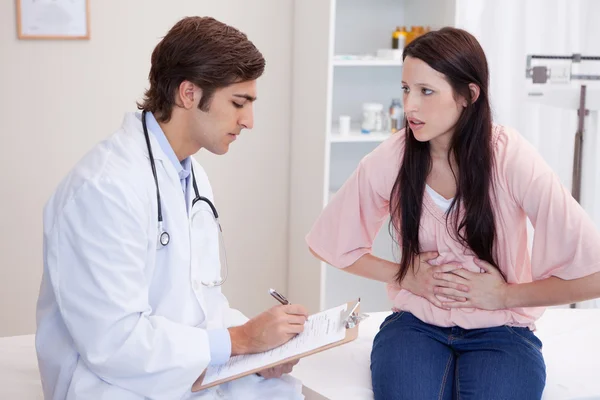 Manliga läkare skriva ner kvinnliga patienter symtom — Stockfoto