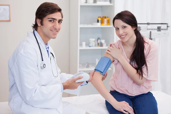 Smiling doctor taking patients blood pressure — Stock Photo, Image