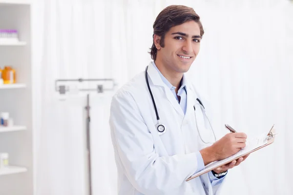 Side view of smiling doctor taking notes — Stock Photo, Image