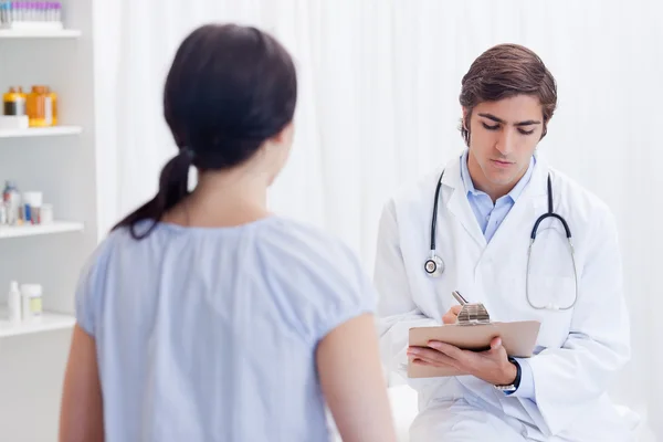 Physician taking notes while patient is talking — Stock Photo, Image