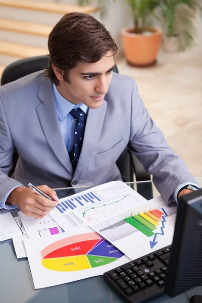 Businessman analyzing statistics at his desk — Stock Photo, Image