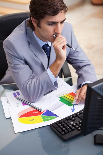 Businessman working on statistics at his desk — Stock Photo, Image