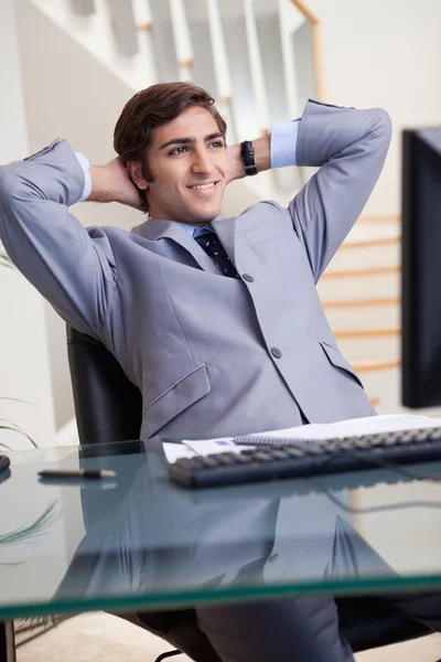 Empresário sorridente inclinado para trás em seu escritório — Fotografia de Stock