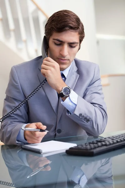 Uomo d'affari prendere appunti mentre al telefono — Foto Stock