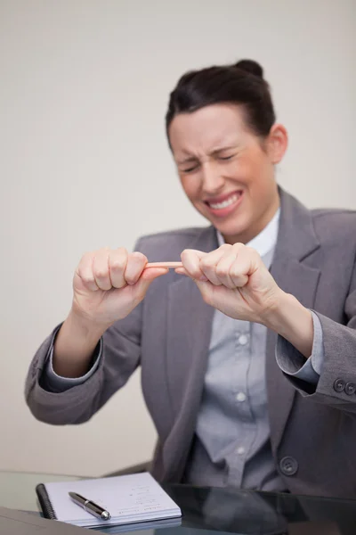Rozzlobený podnikatelka snaží prolomit tužka — Stock fotografie