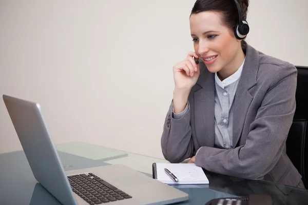 Businesswoman with headset on her laptop — Stock Photo, Image