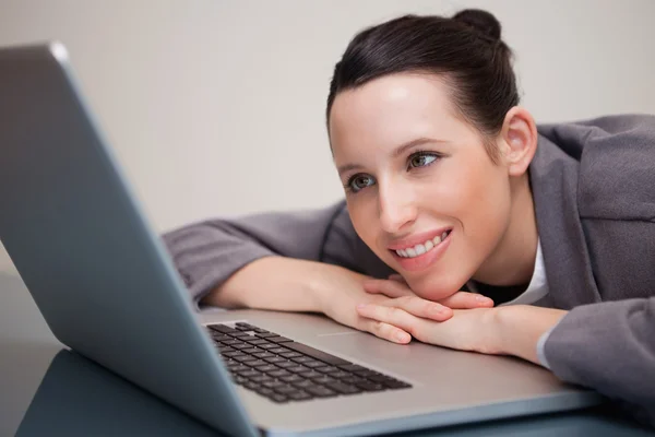 Uśmiechnięta kobieta nachylając się przeciwko jej laptop — Zdjęcie stockowe