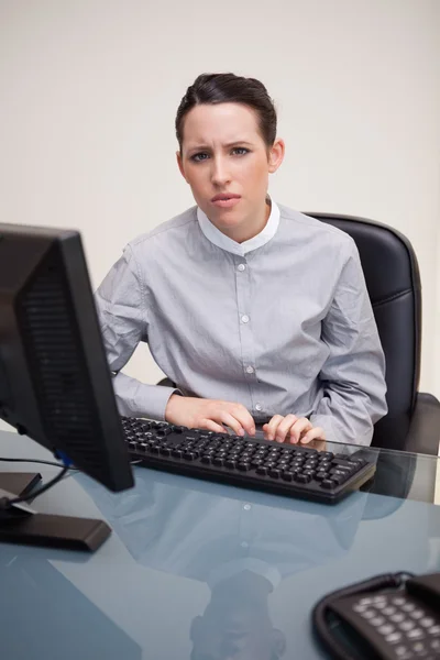 Geschäftsfrau hinter ihrem Schreibtisch sieht verwirrt aus — Stockfoto