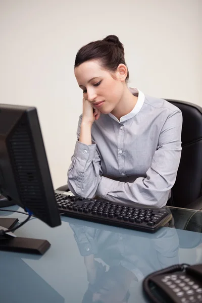 Affärskvinna sitter uttråkad på sitt skrivbord — Stockfoto