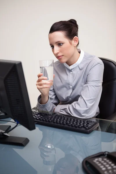 Affärskvinna på hennes skrivbord med ett glas vatten — Stockfoto
