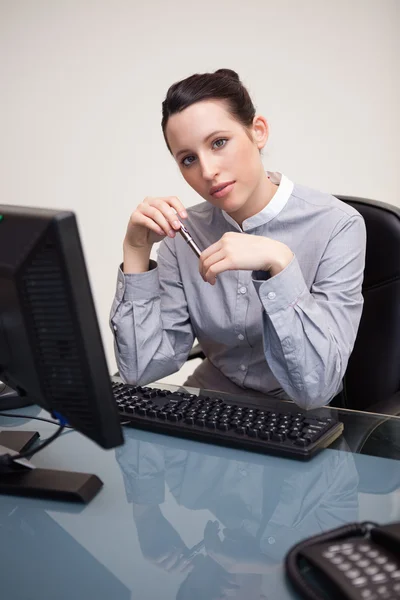 Empresaria sosteniendo pluma sentada detrás de un escritorio —  Fotos de Stock