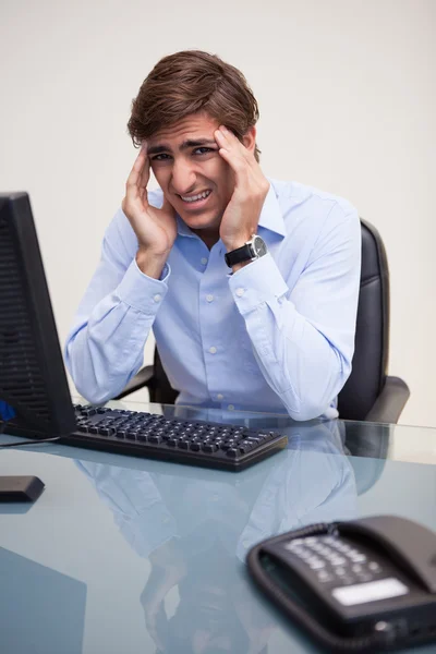 Empresário com dor de cabeça em seu escritório — Fotografia de Stock