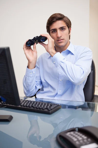 Empresário com binóculos em seu escritório — Fotografia de Stock