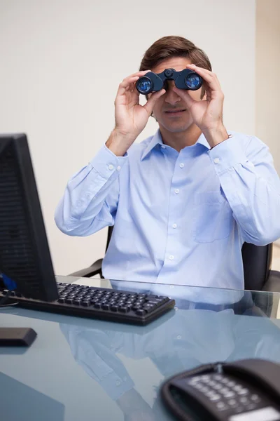 Affärsman tittar genom kikare i hans kontor — Stockfoto