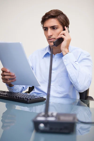 Affärsman hålla pappersarbete på telefonen — Stockfoto