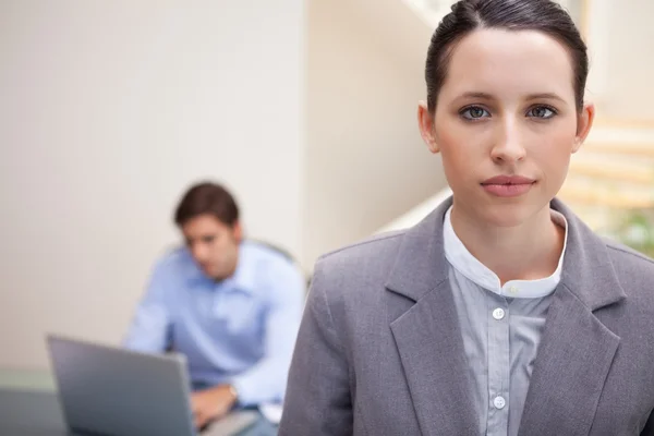 Geschäftsfrau mit Kollege auf Laptop hinter ihr — Stockfoto