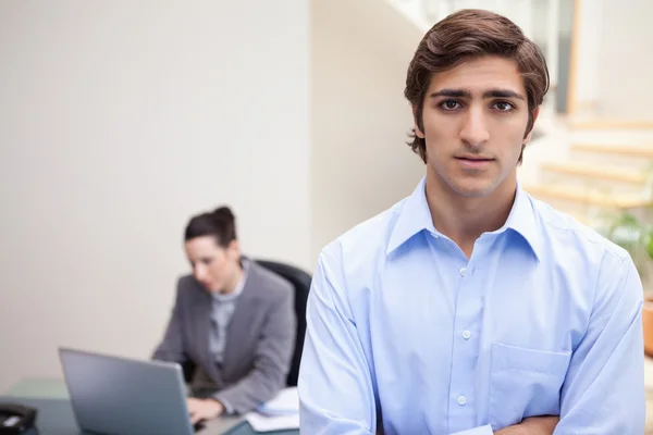 Businessman with colleague on her notebook behind him — Stock Photo, Image