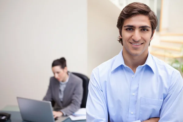 Empresário sorridente com colega em seu laptop atrás dele — Fotografia de Stock