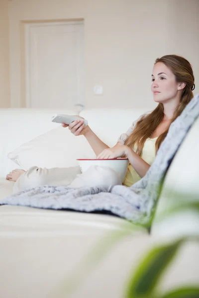 Mulher no sofá desfrutando de um filme com pipocas — Fotografia de Stock