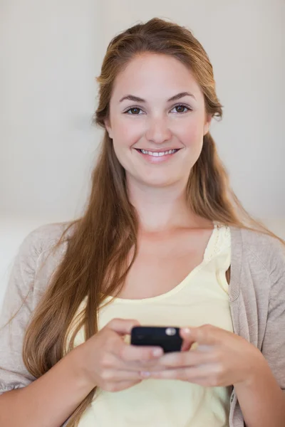 Femme souriante tenant son téléphone portable — Photo