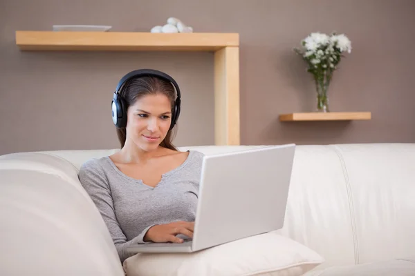 Vrouw met hoofdtelefoon op haar laptop — Stockfoto