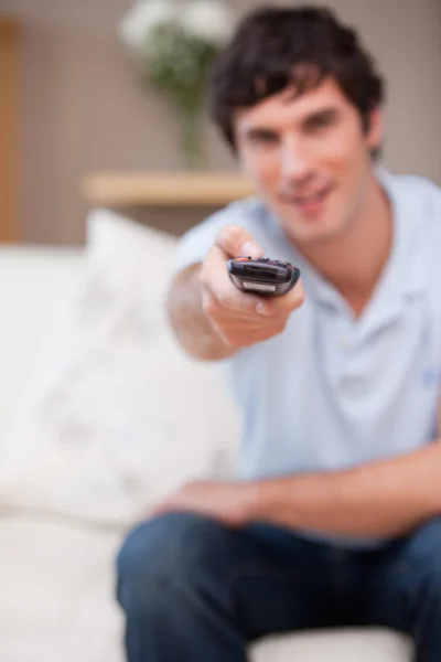 Remote being used by man on the sofa — Stock Photo, Image