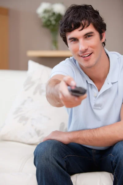 Mann auf dem Sofa schaltet den Fernseher ein — Stockfoto