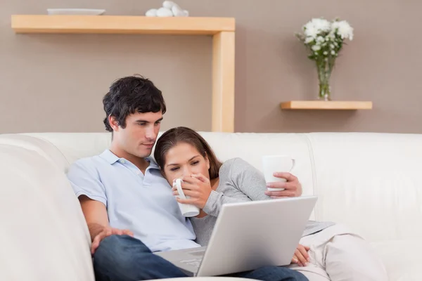 快乐的夫妇与他们的笔记本电脑在沙发上 — 图库照片