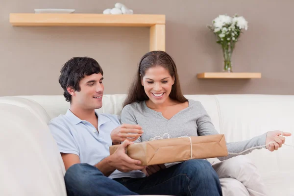 Couple opening parcel on the sofa — Stock Photo, Image