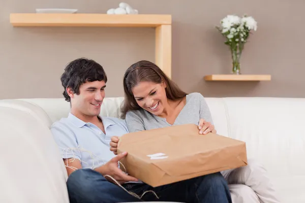 Couple on the sofa opening parcel — Stock Photo, Image