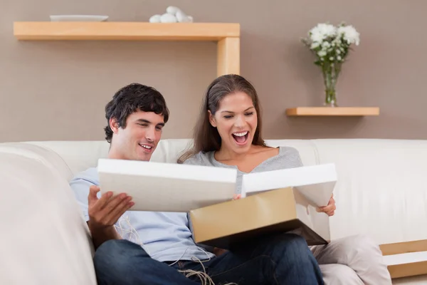 Couple on the couch opening parcel — Stock Photo, Image