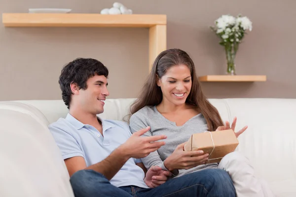 Couple on the sofa with parcel — Stock Photo, Image