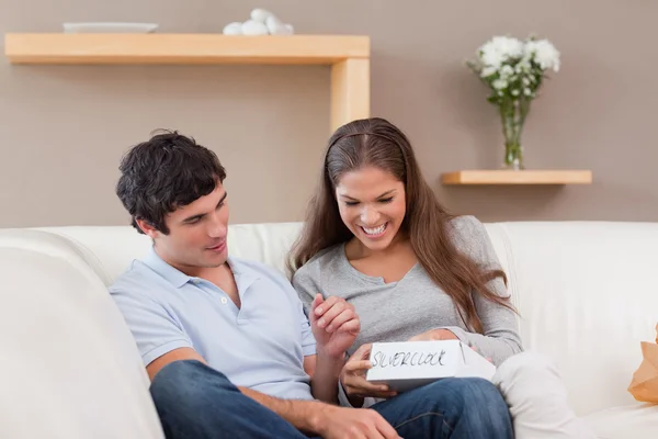 Woman opening present from her boyfriend on the sofa — Stock Photo, Image