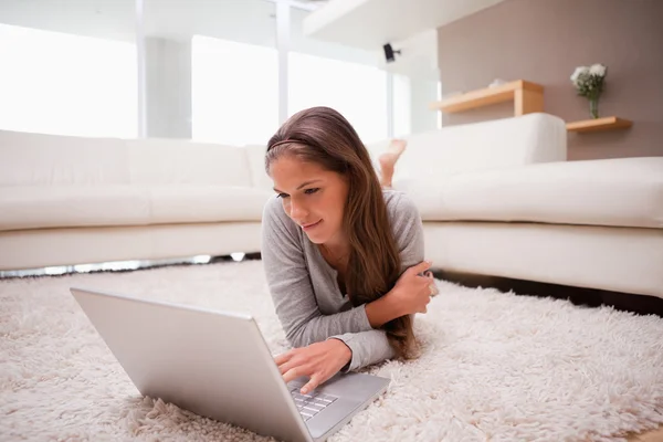 Vrouw met laptop op de vloer liggen — Stockfoto