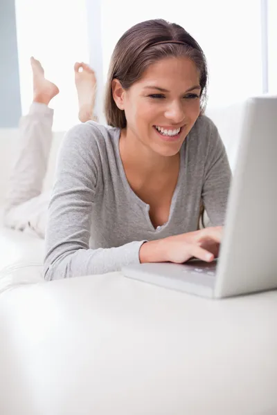 Uśmiechający się online na czacie na jej kanapie — Zdjęcie stockowe