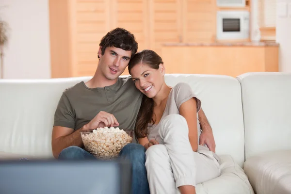 Ζευγάρι με μπολ με ποπ κορν, βλέποντας μια ταινία στον καναπέ — Φωτογραφία Αρχείου