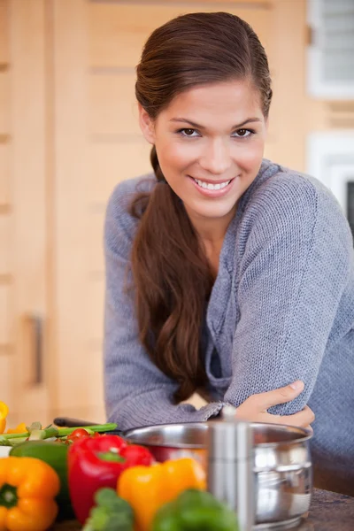 Усміхнена жінка спирається на кухонну стійку — стокове фото