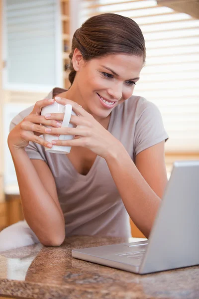 Mulher com café e laptop na cozinha — Fotografia de Stock
