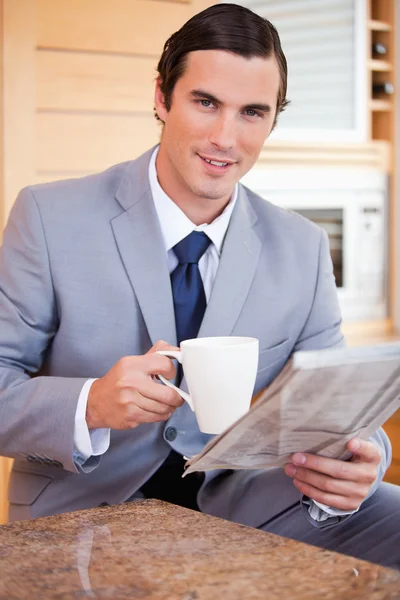 Businessman having coffee and reading news in the kitchen — Stock Photo, Image