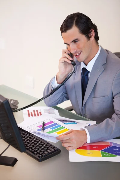 Empresário sorridente falando sobre estatísticas ao telefone — Fotografia de Stock