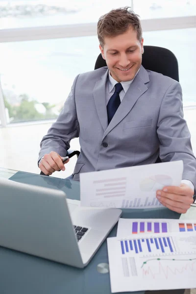 Hombre de negocios sonriente mirando los resultados de la investigación de mercado —  Fotos de Stock